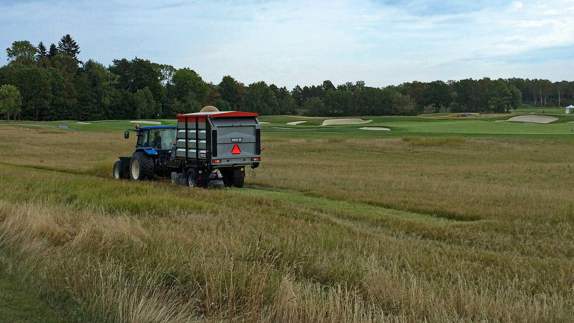 Vacuum trailer mowing and collecting on a golf course