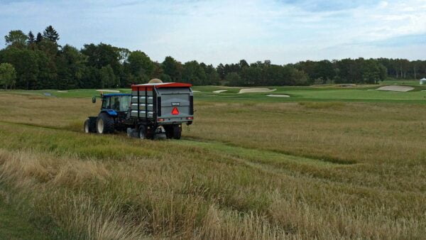 Vacuum trailer mowing and collecting on a golf course