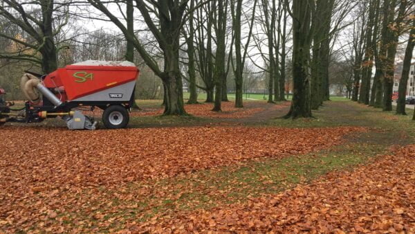 Vacuum trailer sweeping and collecting leaves in park